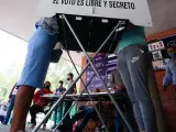 Dos personas, en una cabina electoral en México.