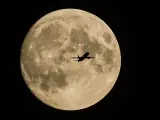 Un avión despega del aeropuerto de Moscú (Rusia), con la enorme superluna de fresa al fondo.
