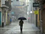 Un hombre camina, este lunes, bajo una intensa lluvia por el centro de la ciudad de Gandía, en Valencia.