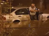 Un hombre trata de salir de su vehículo tras las fuertes lluvias en Fuenlabrada.