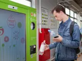Un joven introduce envases de plástico en una máquina Reverse vending en Moscú