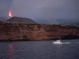 Una embarcación regresa al puerto de Tazacorte, en La Palma, en la zona donde se prevé que podría llegar la colada de lava procedente del volcán de Cumbre Vieja (al fondo).