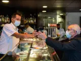 Un camarero escanea el código QR del certificado de vacunación de un cliente en el famoso bar Zurich de la plaza de Cataluña de Barcelona, este viernes, cuando los contagios de coronavirus siguen creciendo en Cataluña, y ha entrado en vigor la obligatoriedad, del pasaporte covid para entrar en bares, restaurantes, gimnasios y residencias. EFE/Enric Fontcuberta