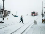 Oficial de conductor de tren a pie cruzan las vías del ferrocarril Tsugaru en la nieve del invierno en la estación de Goshogawara en Aomori (Japón)