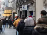 Decenas de personas hacen cola para comprar un décimo para la lotería de Navidad en Madrid.