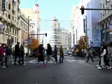 Varios peatones cruzan la Gran Vía madrileña, un día de esta Navidad.