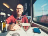 Turista bebe vino mientras realiza su viaje en tren.