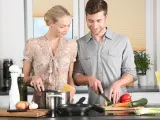 Una pareja cocina con la sartén