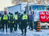 Agentes policiales pasan junto a la zona donde se concentran las protestas de los grupos antivacunas, frente al Parlamento de Canadá, en Ottawa.