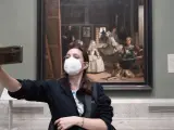 Una persona protegida con mascarilla se realiza una fotografía con Las Meninas de Velázquez al fondo, en el Museo del Prado