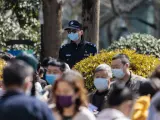 Un oficial de policía supervisa a las personas que hacen cola para las pruebas masivas de COVID-19 en un parque público, en Shanghái, China.