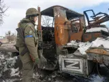 Imagen de un soldado ucraniano ante un camión militar ruso calcinado.