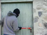 Un ladrón intentando entrar en una casa.