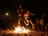 Varios jóvenes saltan una hoguera en la playa de Riazor (A Coruña) durante la tradicional noche de San Juan.
