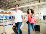 Young couple rushes through the airport to catch a flight.