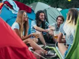 Group of friends relaxing and having fun outside tents while at the music festival. Young and cheerful couple on a music festival.