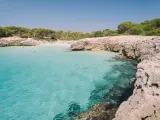 Esta es una de las calas más pequeñas y recónditas de la isla. Con aguas turquesas y arena blanca, se sitúa cerca de Ciutadella,y sus apenas 20 metros de playa virgen la convierten en una de las más pequeñas, pero también de las más especiales.