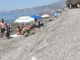 Varias personas en Playa Granada, en Motril, donde el temporal ha dejado un escalón en la orilla.