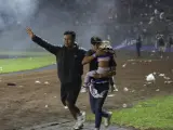 Dos personas tratan de evacuar a una niña del estadio.
