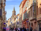 TOULOUSE, FRANCE: APRIL 01, 2018: People walking in the street in te city of Toulouse, with San Sernin basilica in the background