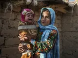 Una ni&ntilde;a sostiene a su hermano frente a su casa, Afganist&aacute;n
