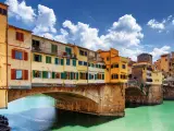 Side view of medieval stone bridge Ponte Vecchio over the Arno River in Florence, Tuscany, Italy. View from the Lungarno degli Archibusieri. Florence is a popular tourist destination of Europe.