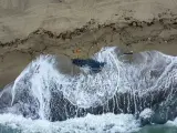 Vista de parte de los restos de un bote volcado que fue arrastrado a tierra en una playa cerca de Cutro, en el sur de Italia.