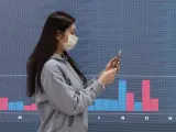 Una mujer en Seúl frente a una pantalla electrónica que muestra el precio de bitcoin en plena crisis por el Silicon Valley Bank (SVB).