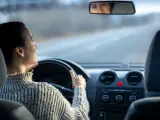 Una mujer mirando por el retrovisor interior mientras conduce.