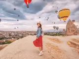 Turista en Capadocia con los icónicos globos de fondo.