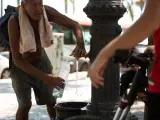 Un hombre rellena una botella de agua en una fuente en el parque de la Barceloneta, a 13 de julio de 2022.