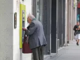 Un anciano saca dinero de un cajero de la capital.