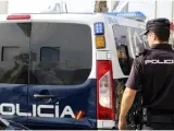 Imagen de archivo de un agente y un furgón de la Policía Nacional.
