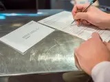 Una persona rellena documentos tras solicitar el voto por correo en el Edificio de Correos