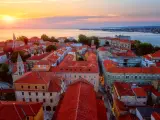 Top view of Zadar old town at sunset from the tower of Zadar cathedral, Dalmatia, Croatia. Scenic cityscape with historical architecture, red tiled roofs, sea, sky and sun, outdoor travel background