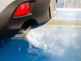 Un coche con motor de combustión expulsando humo procedente de su tubo de escape a la atmósfera.