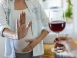 Mujer embarazada rechazando copa de vino.