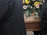 Varias personas llevan un ataúd en un entierro.