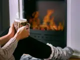 Una chica se calienta al fuego en su casa.