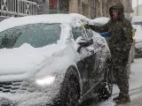 Un hombre retira la nieve de un vehículo durante la nevada de este viernes en Soria.