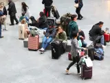 Numerosas personas con maletas esperan para viajar en la estación Almudena Grandes-Atocha Cercanías