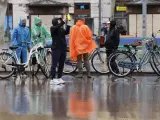 Varias personas se protegen de la lluvia con chubasqueros por las calles de Valencia, este domingo.