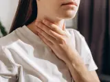 Una mujer tocándose la garganta en símbolo de dolor.