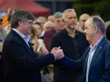 El expresidente de la Generalitat y cabeza de lista de Junts, Carles Puigdemont (i), saluda al secretario general de Junts per Catalunya, Jordi Turull (d), durante el acto final de campaña de JxCat, este viernes en Elna (Francia).