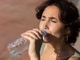 Mujer bebiendo agua al sol.