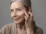 Mujer echándose crema hidratante en la cara.