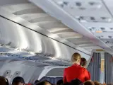 Una azafata atiende a los pasajeros durante un vuelo.