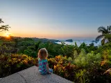 Toddler girl enjoying a vibrant sunrise over the wild untamed coastal beauty of Manuel Antonio National Park on the Pacific Coast of Costa Rica.