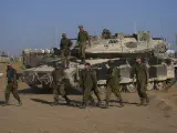 Varios soldados israelíes caminan en una zona de preparación de sus tanques cerca de la frontera con Gaza en el sur de Israel.