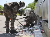 Soldados surcoreanos con equipos de protección revisan la basura enviada desde un globo por Corea del Norte.